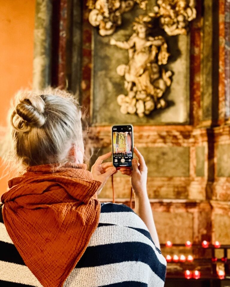 Frau fotografiert mit dem Smartphone den Altar einer Kirche