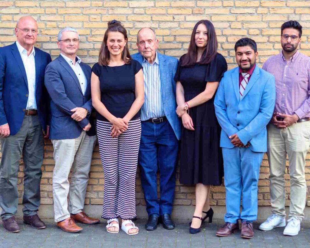 Sieben Mitglieder des Rats der Religionen Frankfurt vor einer Backsteinwand
