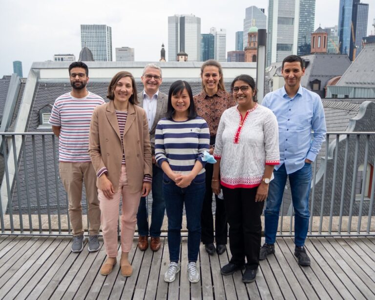 Gruppenfoto von Mitgliedern des Rats der Religionen auf einer Dachterrasse vor der Frankfurter Skyline