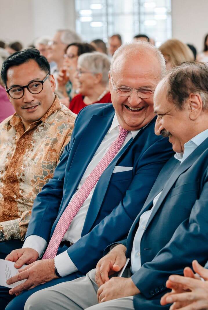 Gäste lachen im Publikum bei einer Veranstaltung des Rats der Religionen Frankfurt