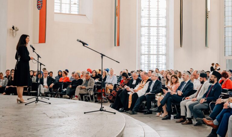Rednerin vor Publikum bei der multireligiösen Feier in der Frankfurter Paulskirche