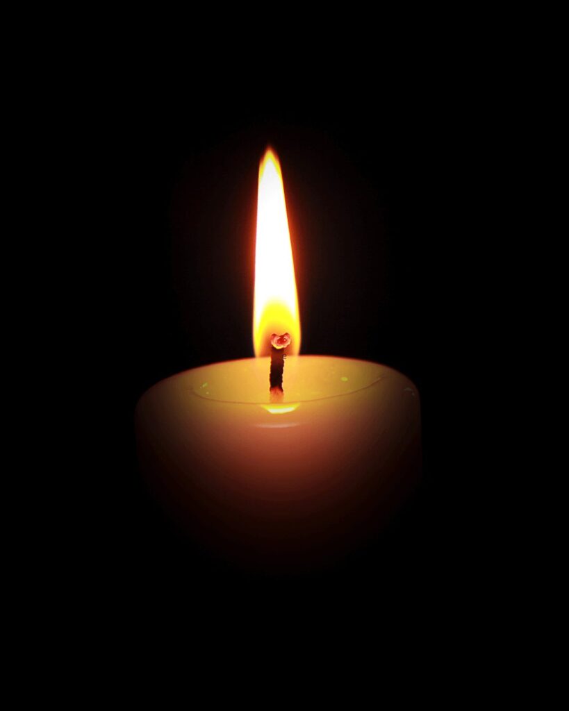 Brennende Kerze vor schwarzem Hintergrund