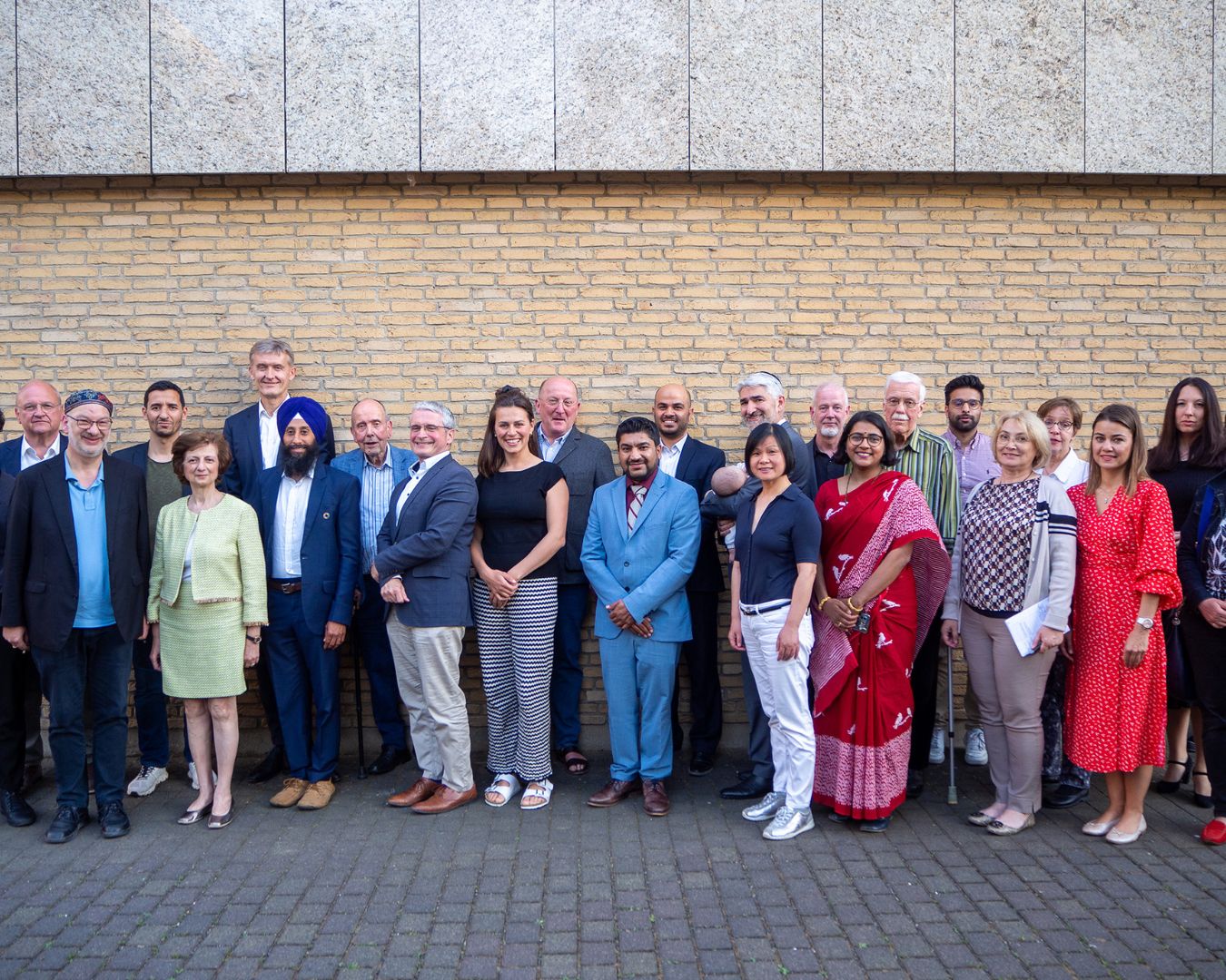 Gruppenfoto der Mitglieder des Rats der Religionen Frankfurt vor einer Backsteinwand im Mai 2023
