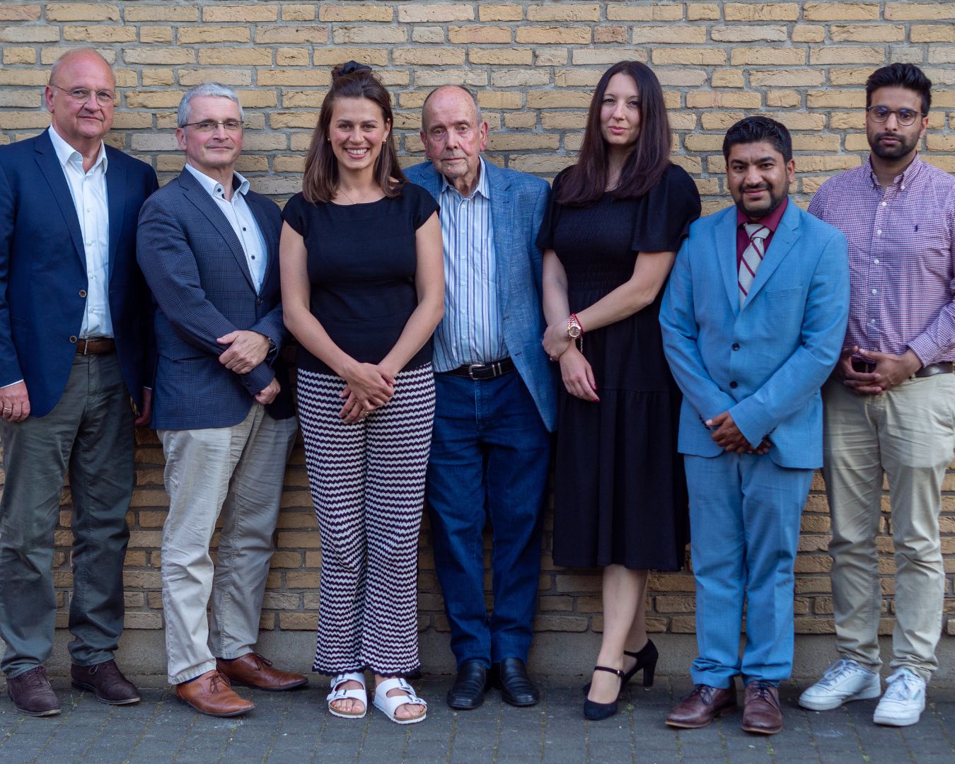 Der im Mai 2023 gewählte Vorstand des Rats der Religionen Frankfurt, sieben Personen vor einer Backsteinwand